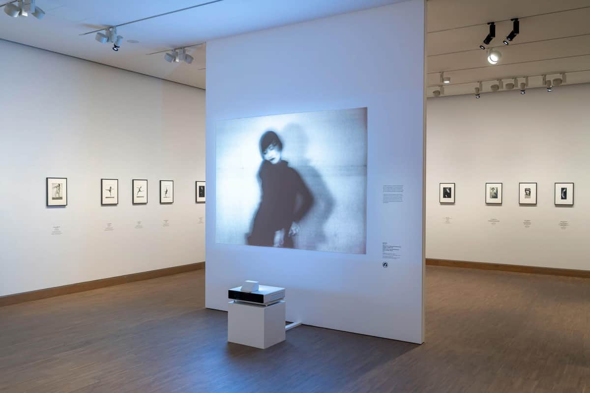 Albertina Museum: Entry Ticket + Audio Guide Art exhibit room featuring a projection of a blurry figure, framed artworks on walls, and a projector on a stand.