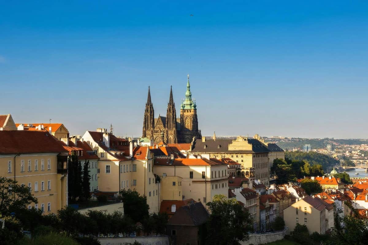 View of a cityscape with historic buildings and a cathedral with tall spires under a bright blue sky.