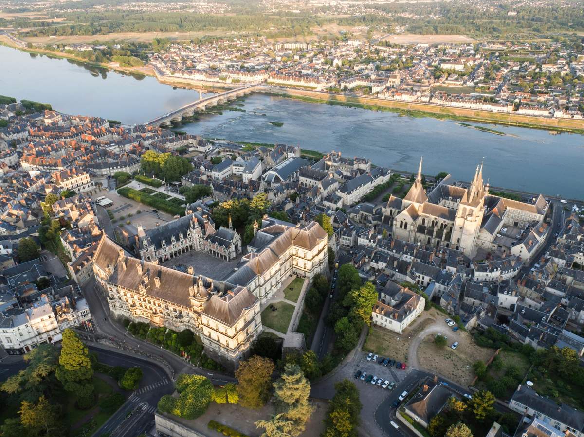 Aerial view of a historic European town with a river, bridge, cathedral, and densely packed buildings.
