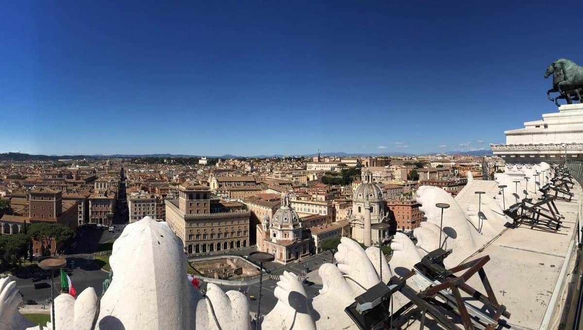 Rome: Palazzo Venezia Reserved Entrance with Museum Panoramic view of a historic city with domed structures and classical buildings under a clear blue sky, seen from a high vantage point.