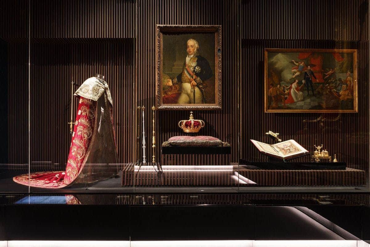 Royal Treasure Museum A museum display featuring regalia, a crown, scepter, open book, and two framed paintings.