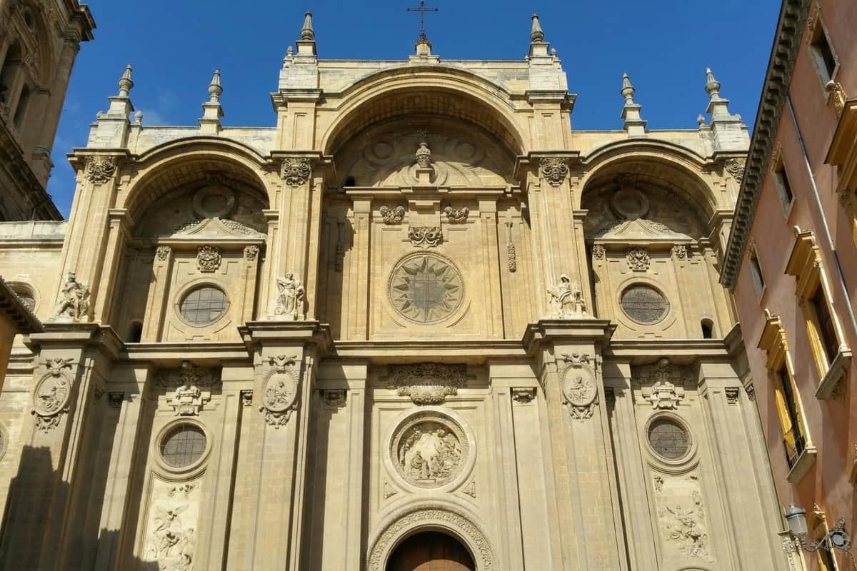 Facciata di una cattedrale storica con dettagli architettonici riccamente decorati, finestre ad arco e sculture, sotto un cielo azzurro e limpido.