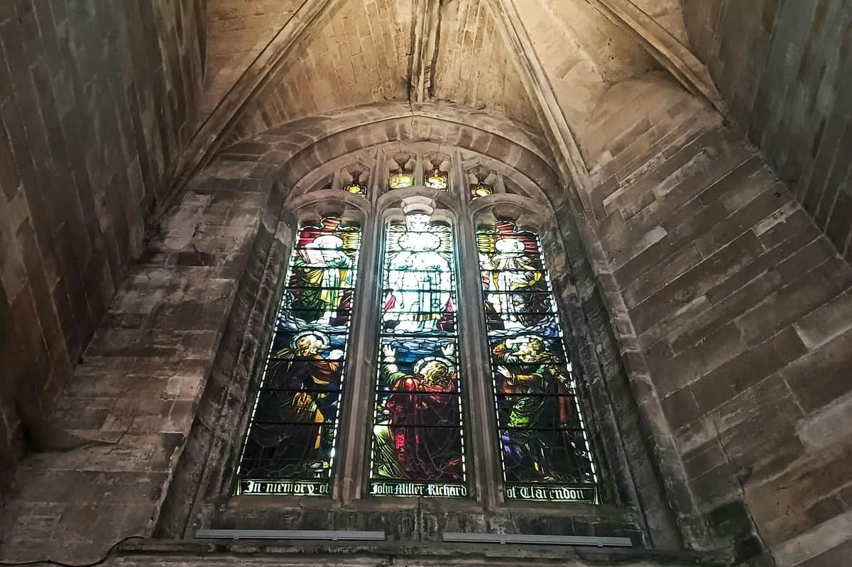 Linlithgow : visite guidée depuis Édimbourg Un grand vitrail dans une église, représentant des scènes religieuses colorées, placé dans une arche gothique en pierre.