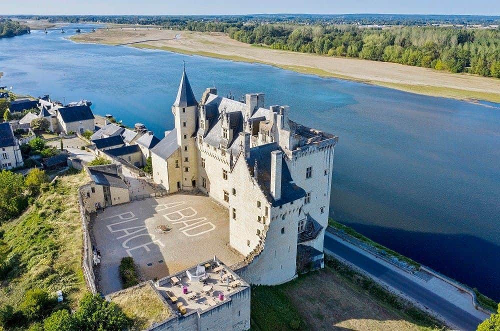 Aerial view of a large castle beside a river, with surrounding small buildings and greenery, and "ABAD PLACE" written on the ground.