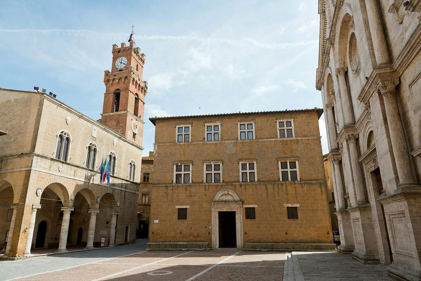 An old town square with historic buildings and a clock tower under a clear sky.