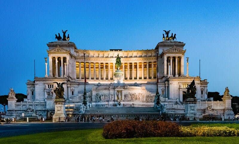 Altar of the Fatherland Illuminated neoclassical building with columns and statues at sunset, featuring a central equestrian monument and ornate sculptures.