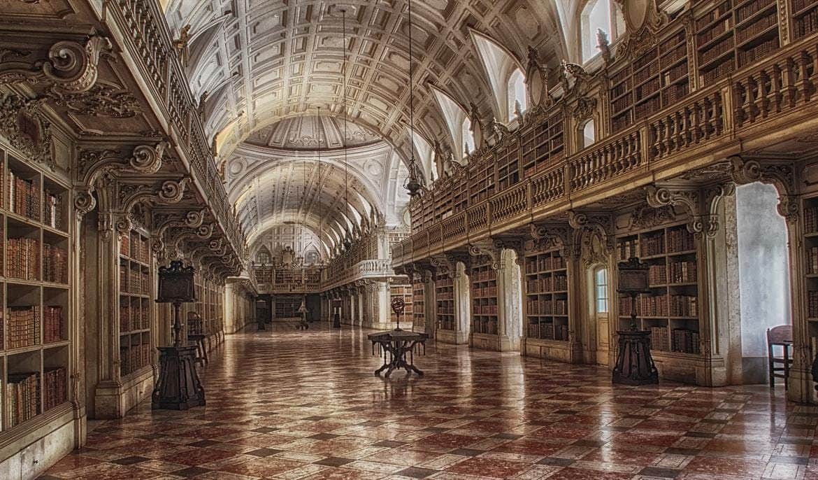 Ornate library interior with arched ceiling, wooden bookshelves, and polished checkered floor. A reading table stands central.
