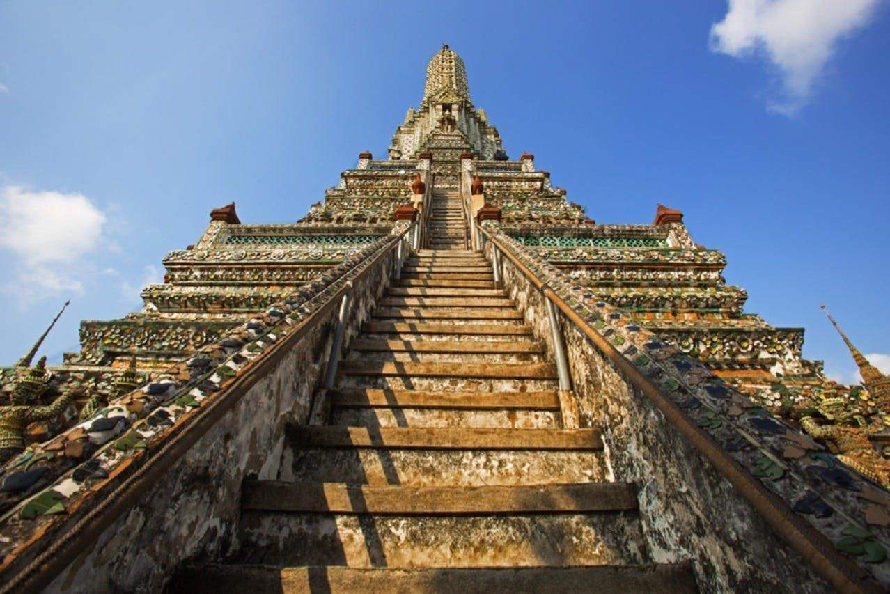 Steep stone staircase leading up to an ornate, ancient temple against a clear blue sky.