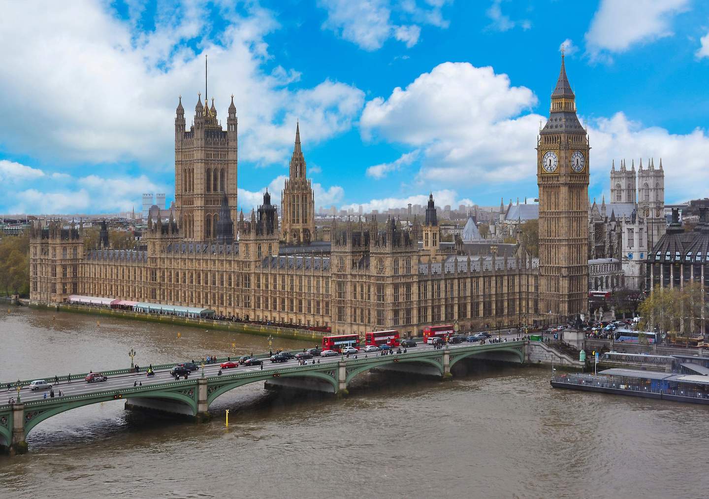 Palais de Westminster Vue du palais de Westminster et de Big Ben avec des bus rouges sur le pont de Westminster au-dessus de la Tamise par une journée partiellement nuageuse.